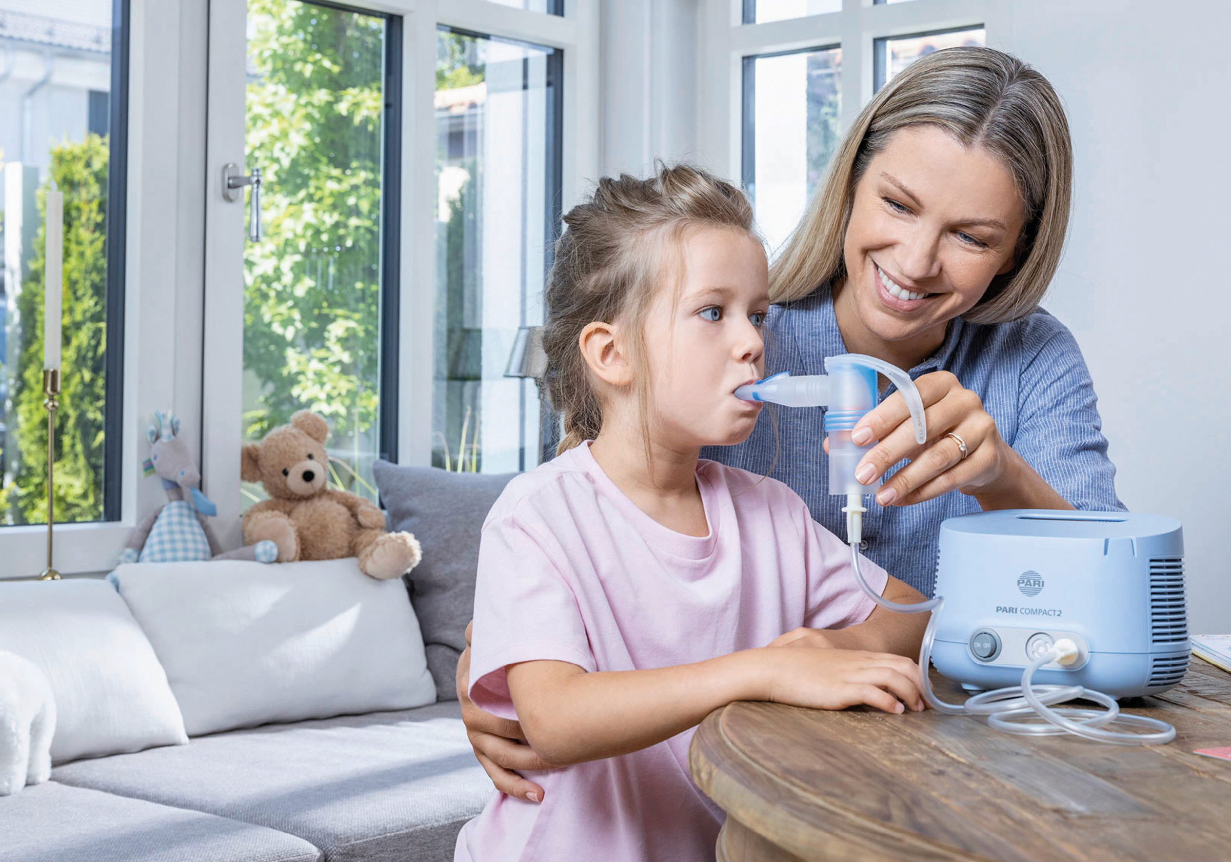 Eine Mutter sitzt mit ihrem Kind und benutzt ein Inhalationsgerät.